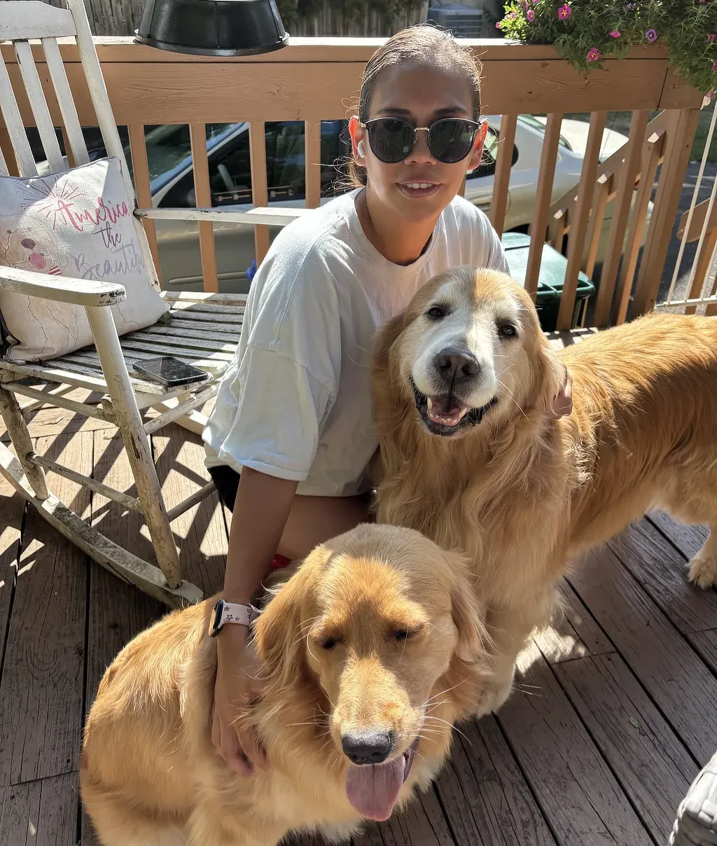Romina sits on the deck with her dogs in a backyard maintained by Dog Butler.